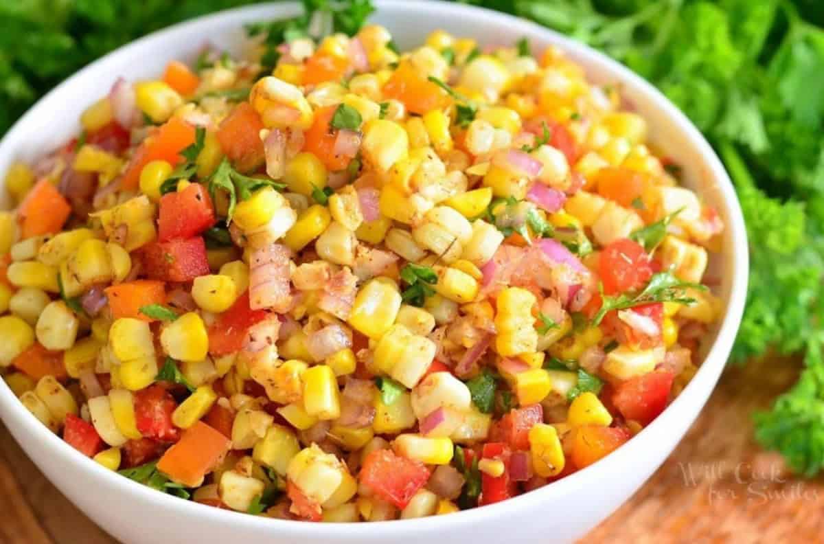 Cajun corn salad in a bowl on a wood surface.