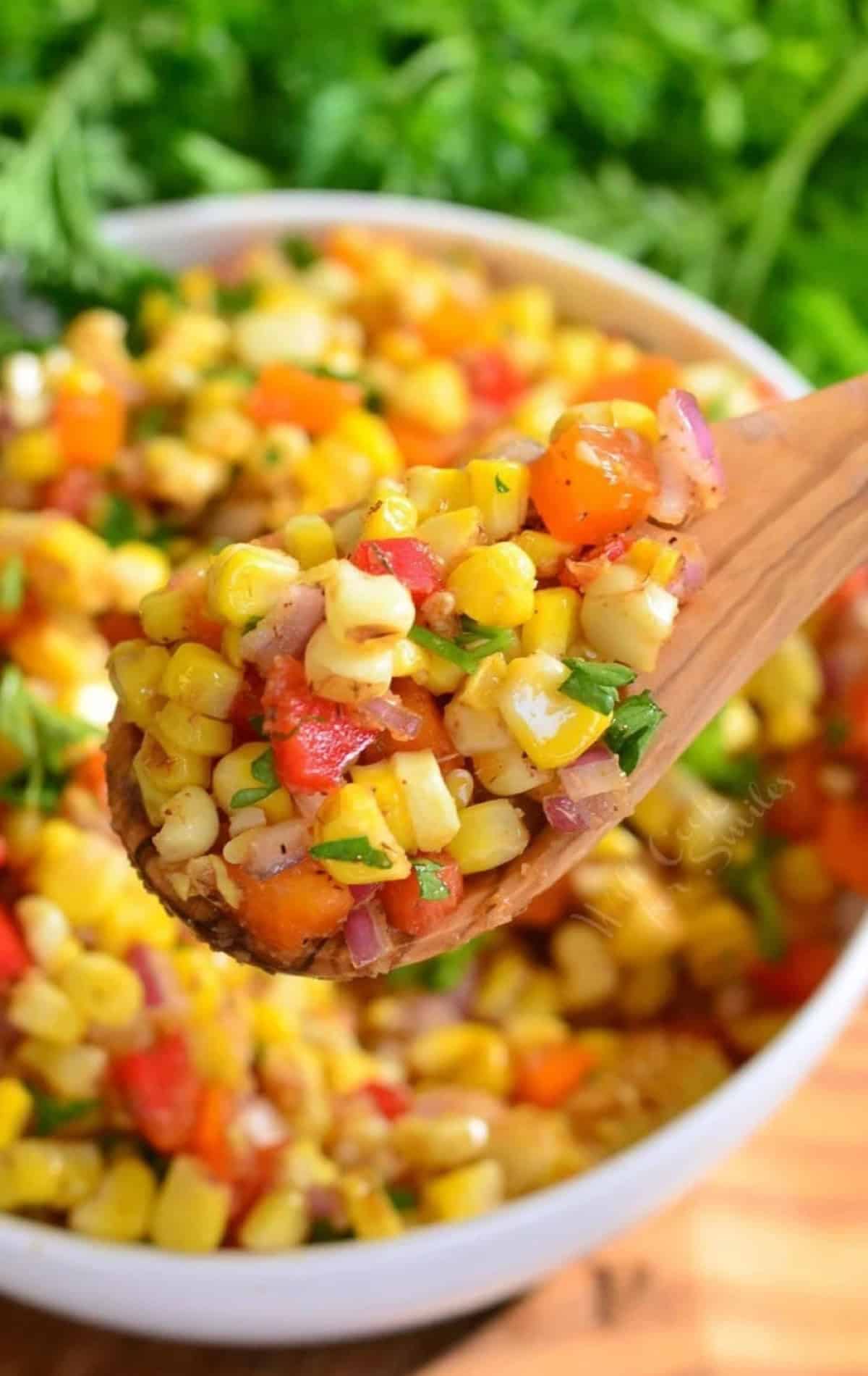 Cajun sorn salad in a bowl with some of the salad on a wooden spoon.