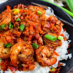 Cajun shrimp over rice in a bowl on a wood surface.