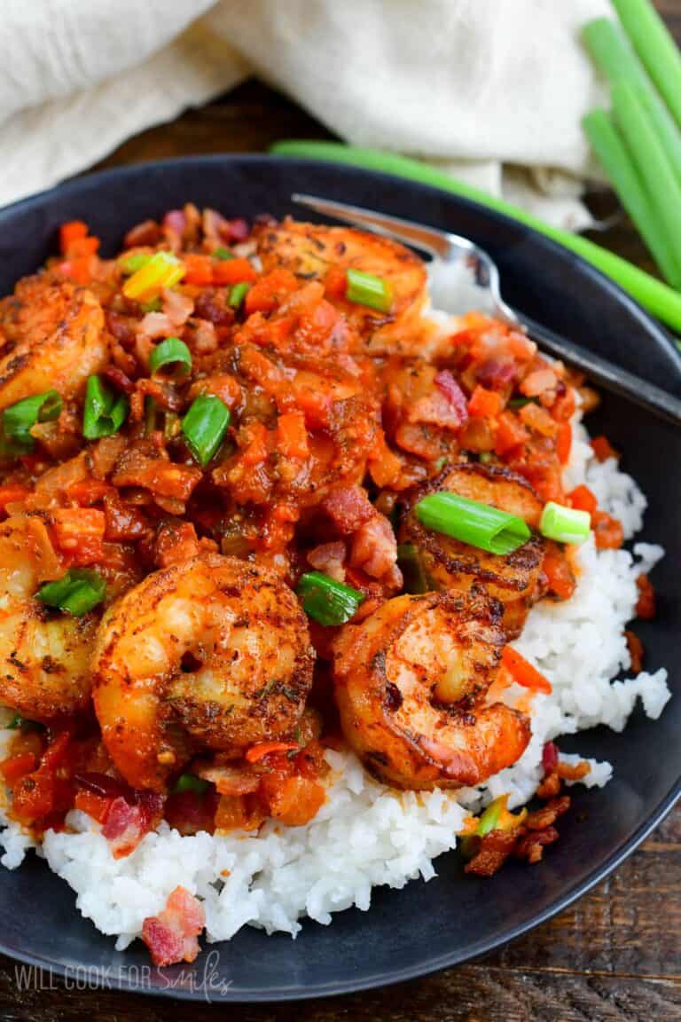 Cajun shrimp over rice in a bowl on a wood surface.