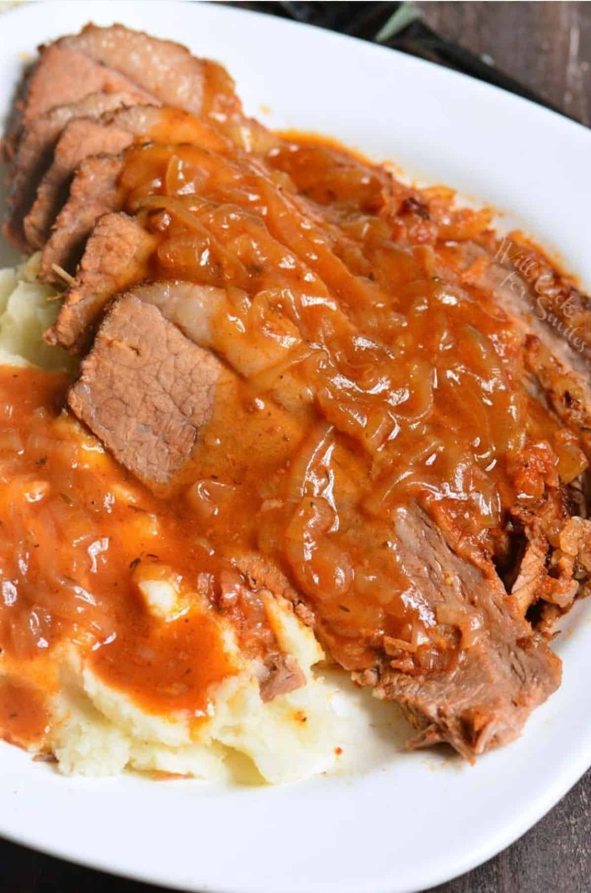 French onion brisket sliced and covered in sauce over fluffy mashed potatoes.