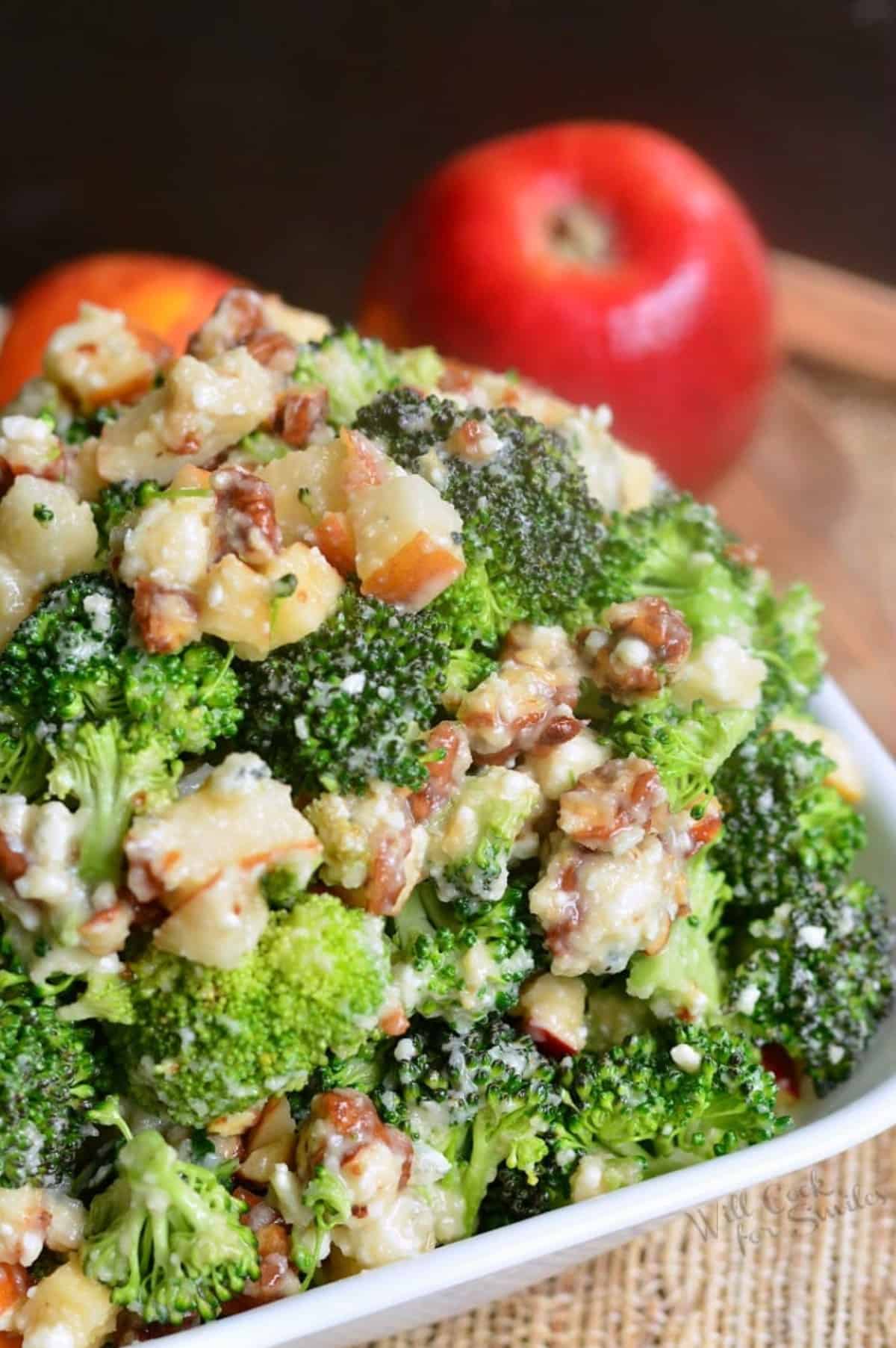bowl full of broccoli salad mixed with pecans, pears, apples, blue cheese and more.