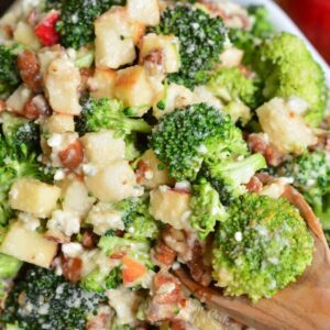 scooping gout some broccoli salad from the bowl filled with pear apple broccoli salad.