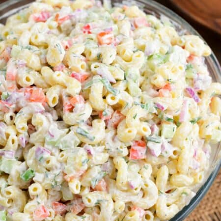 Macaroni salad in a big serving bowl on a wood surface.