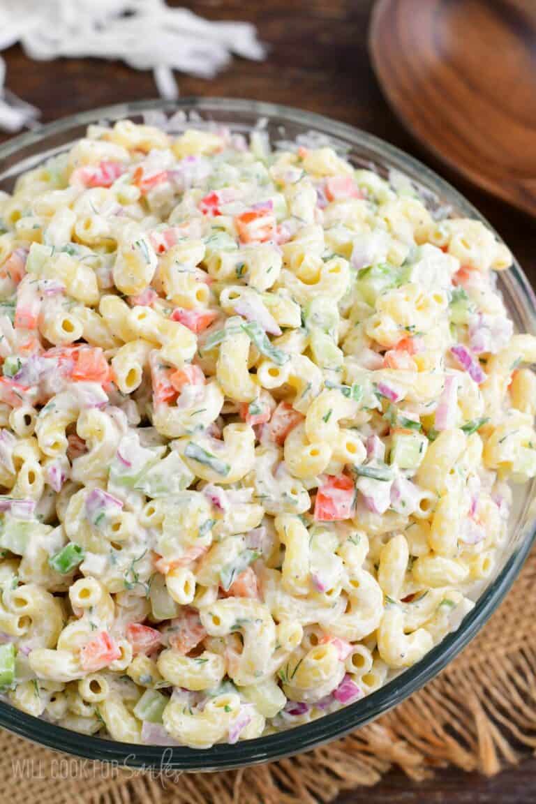 Macaroni salad in a big serving bowl on a wood surface.