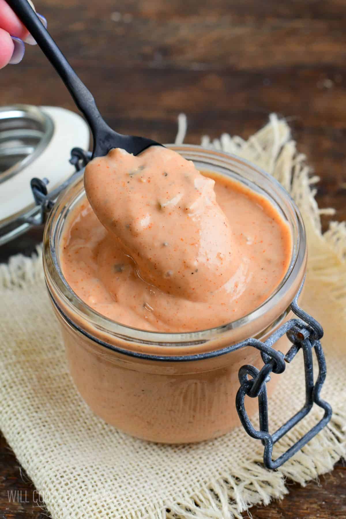 burger sauce in a jar with a spoon scooping some out.