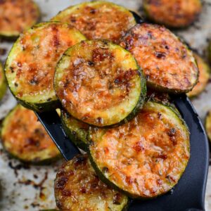 roasted zucchini on a spatula with the rest on a baking sheet.