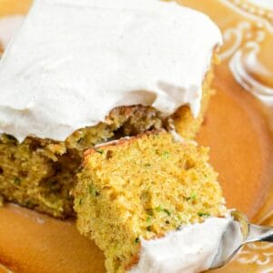 Zucchini cake on a plate with a slice of it on a fork.