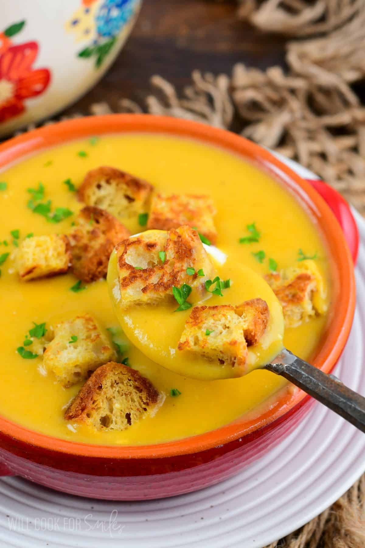 spooning out some Butternut squash potato soup with two croutons as well.