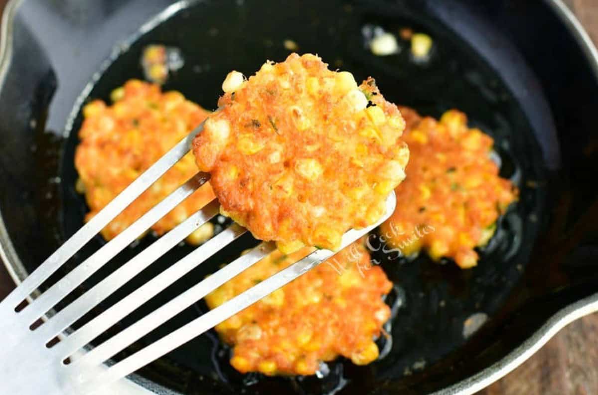 holding one fritter with a metal spatula next to the skillet.