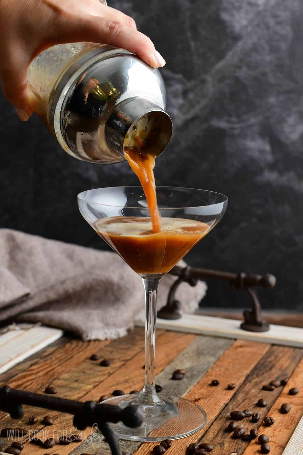 pouring the espresso martini from the shaker into a martini glass.