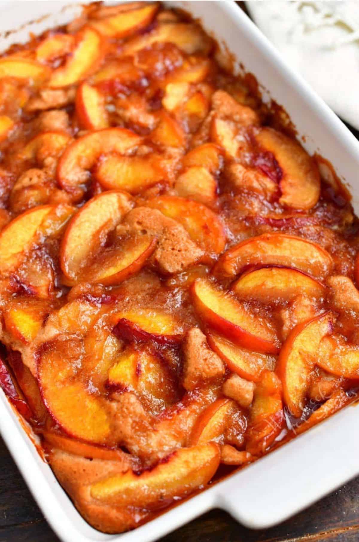 baked peach cobbler in a white baking dish.