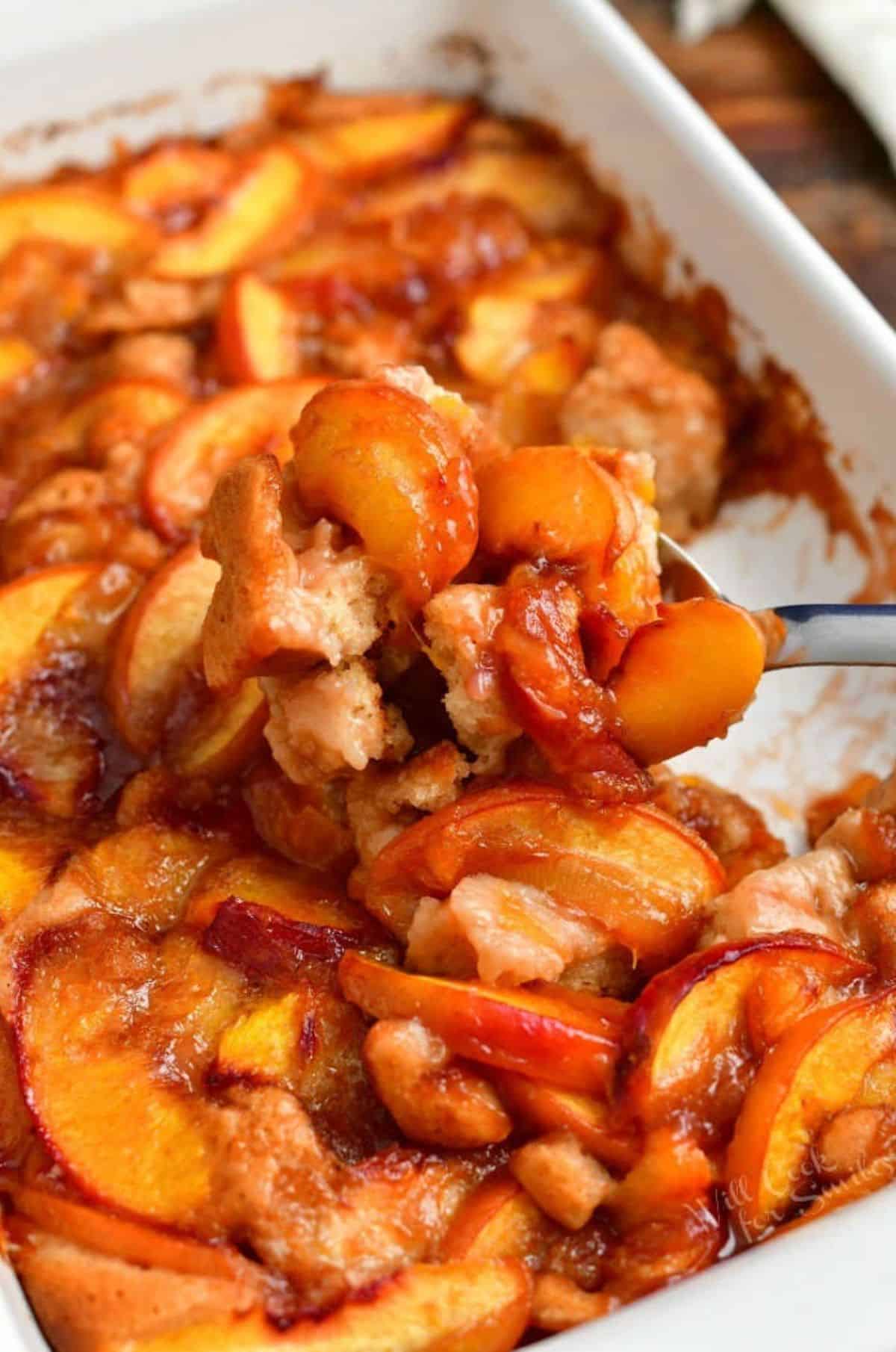 some peach cobbler scooped out on the metal serving spoon.