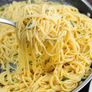 scoooping up pasta out of the pan with a pasta ladle.