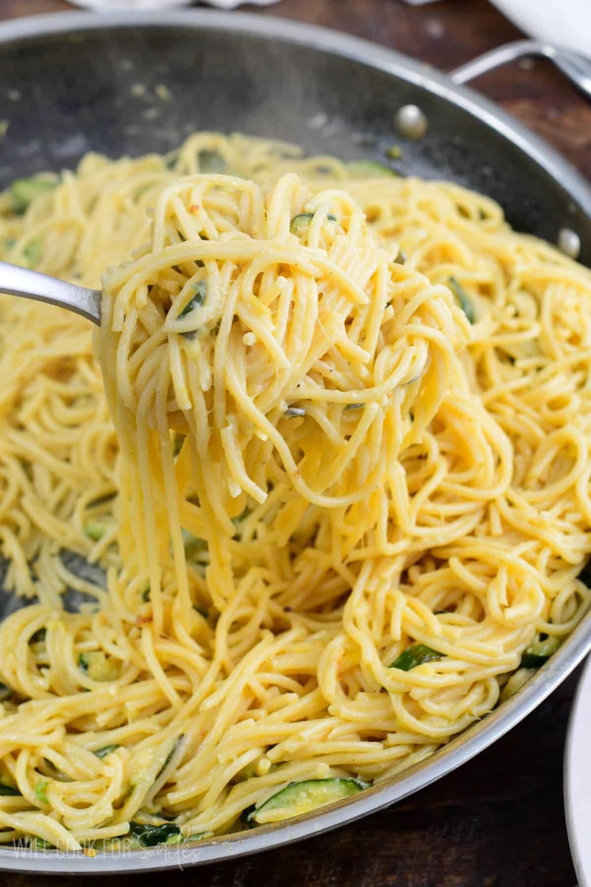 scoooping up pasta out of the pan with a pasta ladle.