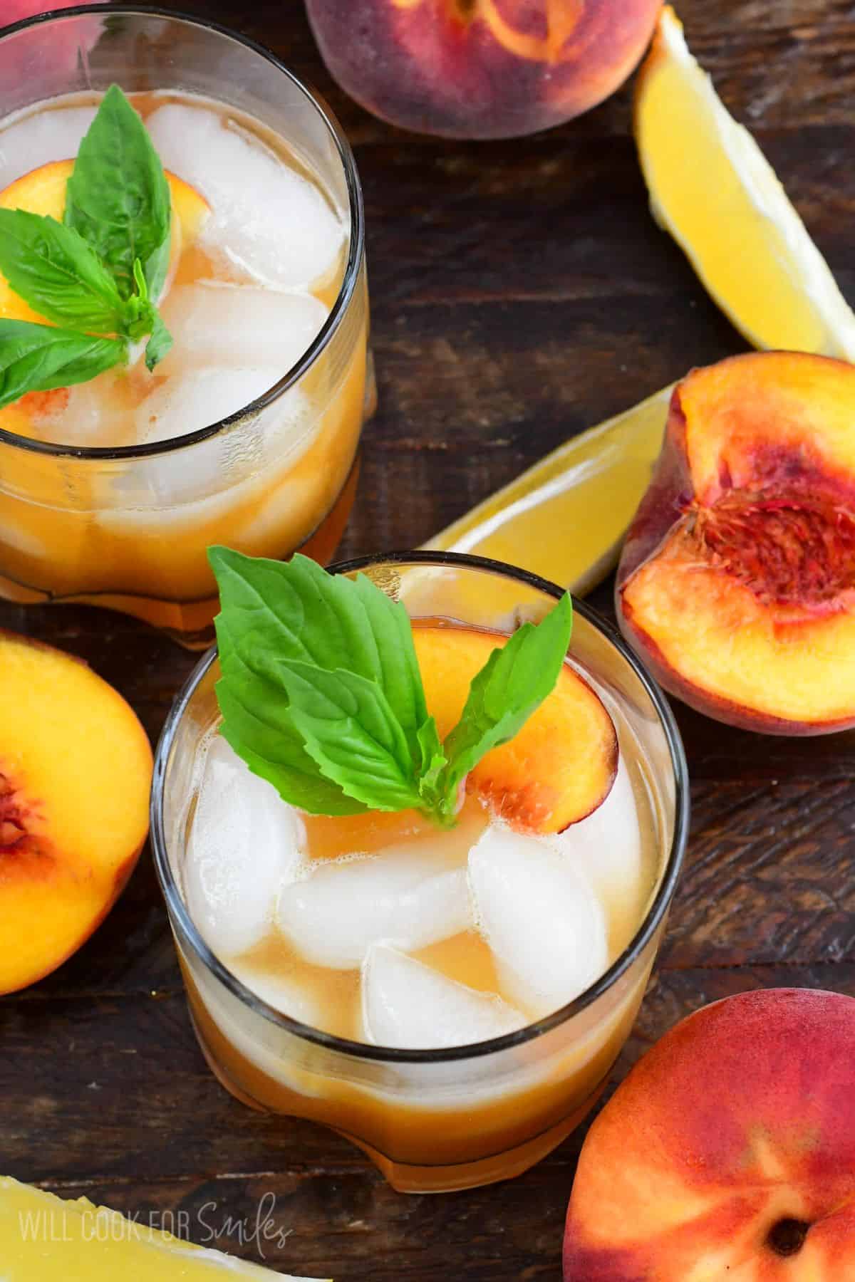 Peach smash bourbon in a glass with peaches and mint as garnish.
