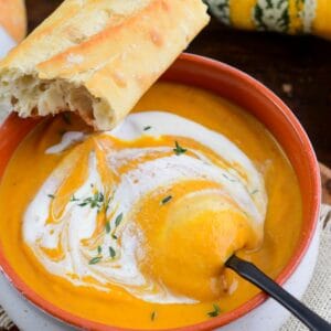 starting to spoon out some pumpkin soup drizzled with cream.