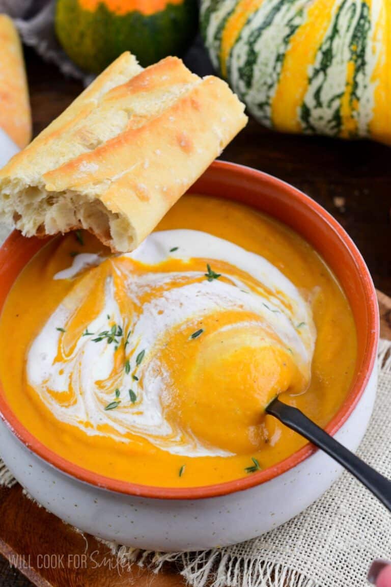 starting to spoon out some pumpkin soup drizzled with cream.