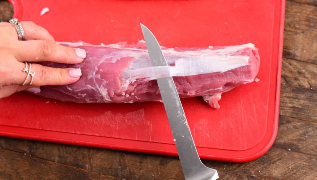 removing silverskin from pork tenderloin with a thin knife.