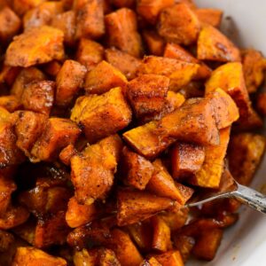 Spiced roasted honeynut sqaush in a bowl with a spoon scooping some out.
