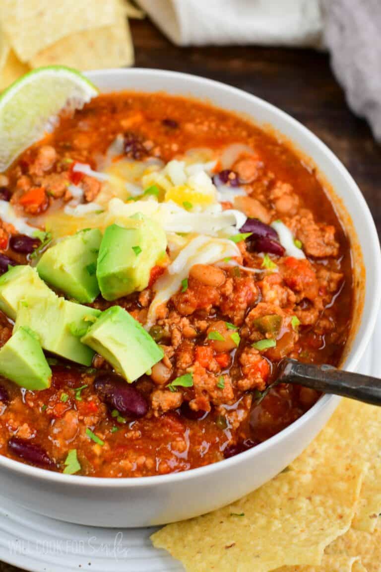 scooping out some turkey chili from a bowl with a metal spoon.