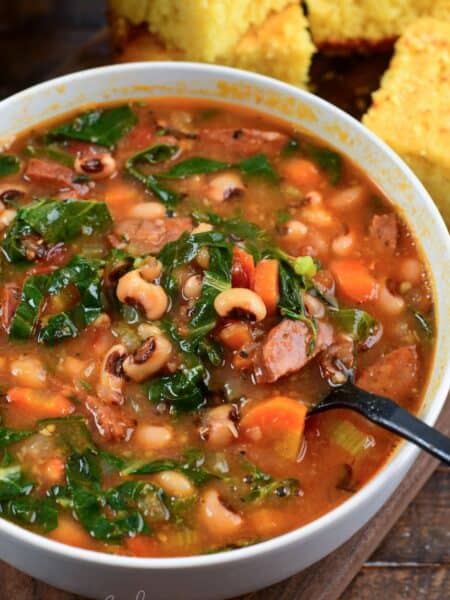 starting to spoon out some Southern black eye pea soup from a bowl next to fresh homemade buttermilk cornbread.