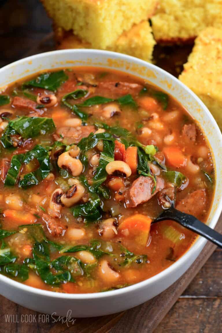 starting to spoon out some Southern black eye pea soup from a bowl next to fresh homemade buttermilk cornbread.