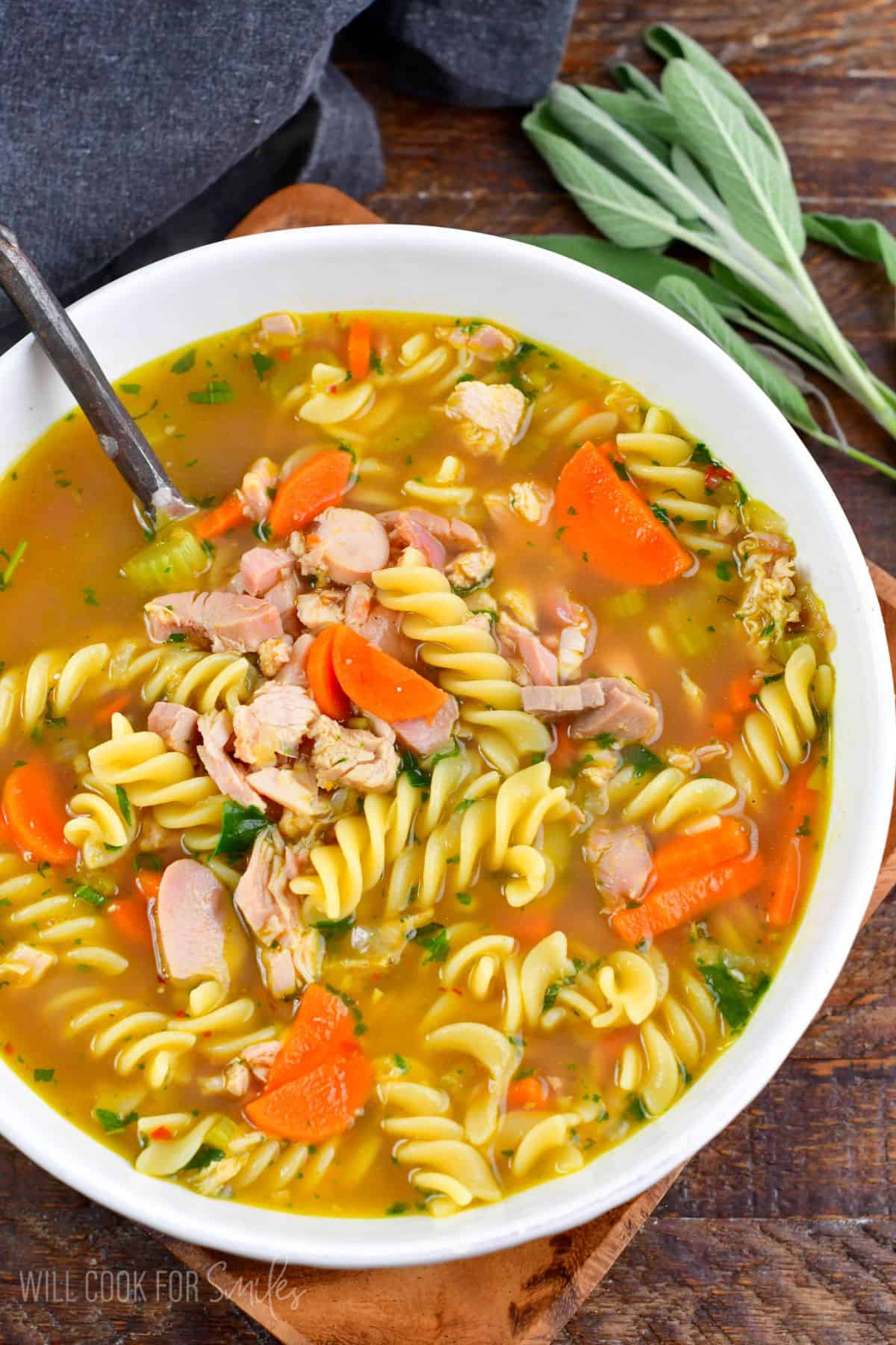 Leftover turkey noodle soup served hot with fresh parsley and sage in a flavorful homemade turkey broth.