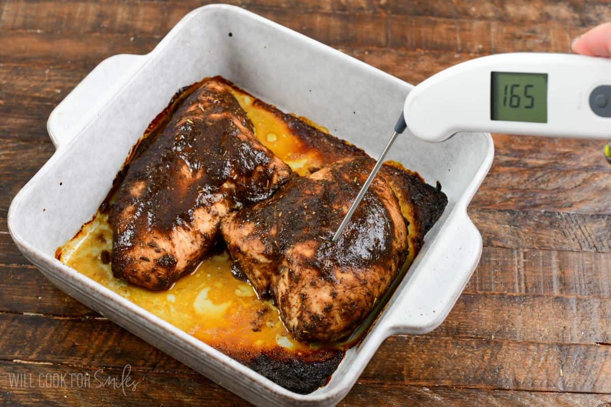 taking temperature of the tender baked turkey tenderloin in a balsamic glaze in a baking dish.