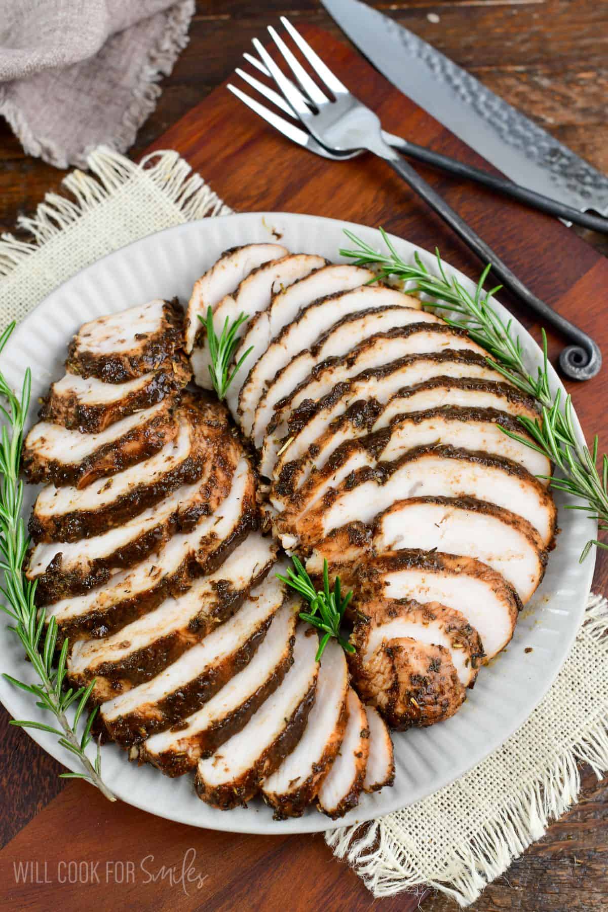 two sliced baked turkey tenderloins in a balsamic mixture layered on the plate.