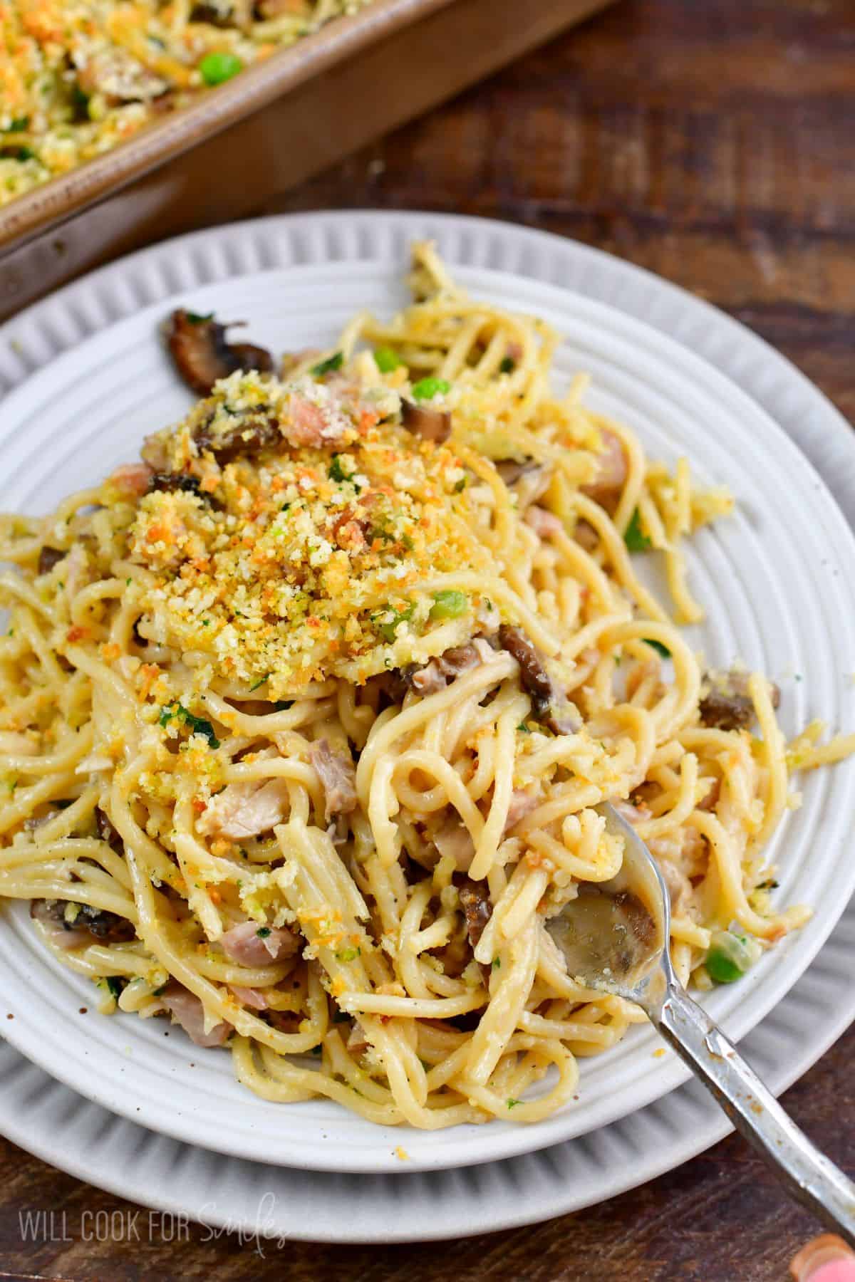 Turkey tetrazzini on a plate with a fork on a wood surface.