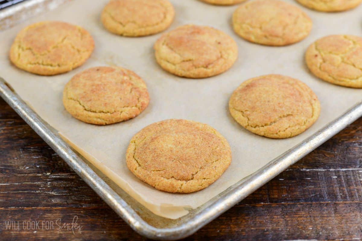 baked cinnamon sugar coated thin crispy and chewy snickerdoodle cookies on baking sheet.
