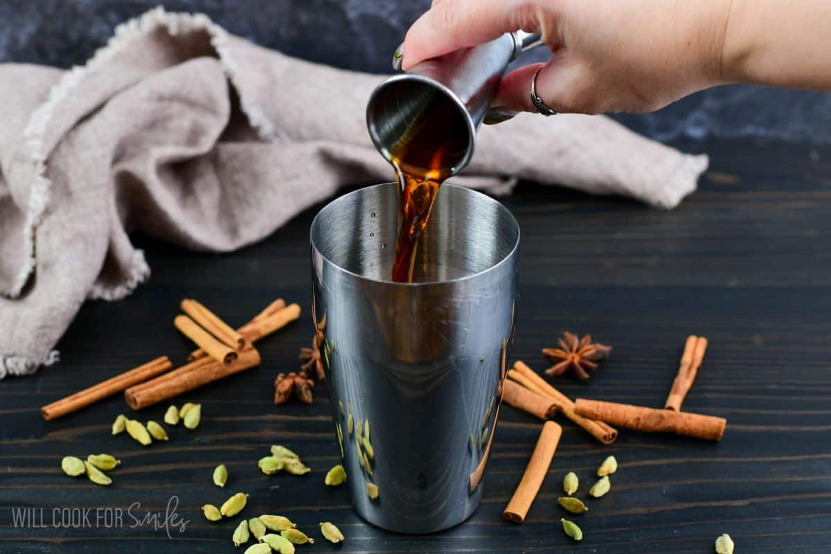 Adding the tea into the shaker on a wood surface.