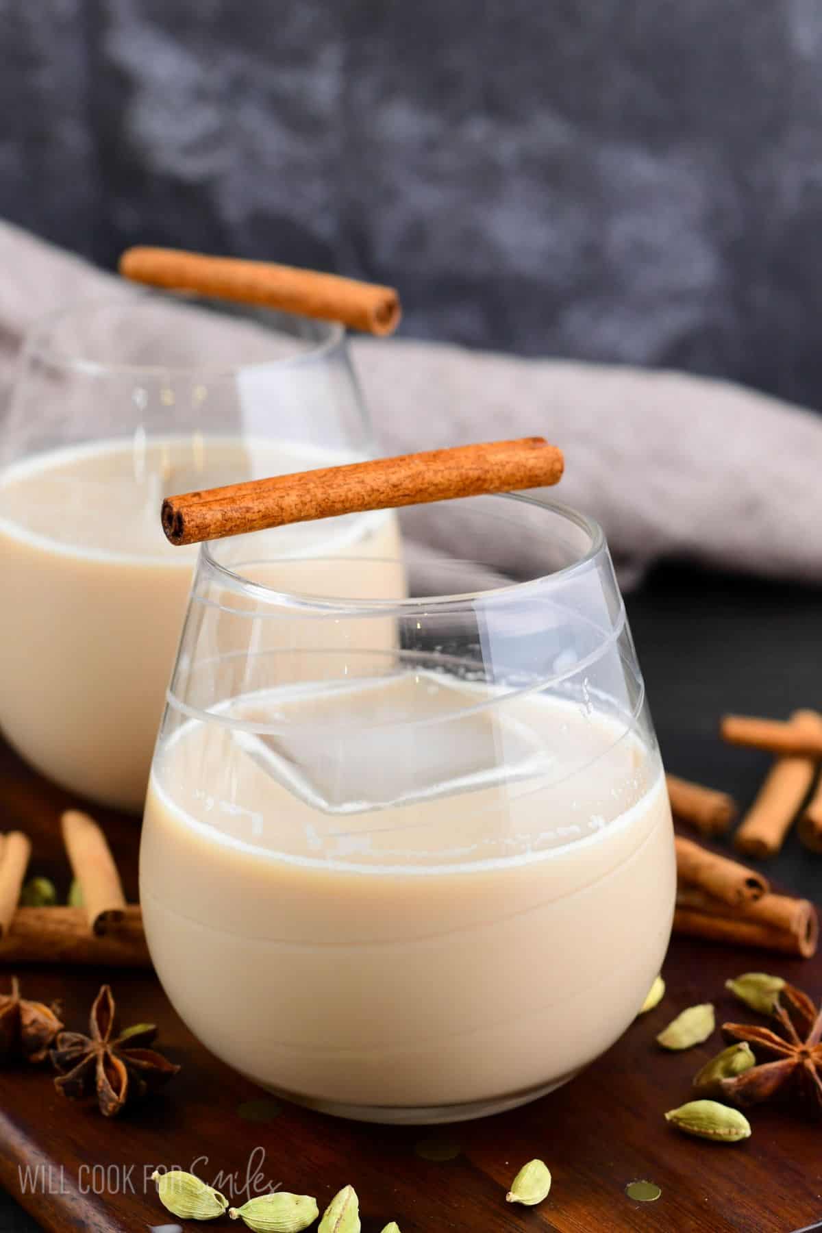 smooth creamy chai cocktail in a glass with an ice cube and cinnamon stick.