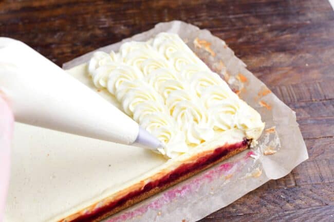 Pipping the frosting on top of Christmas cheesecake bars.
