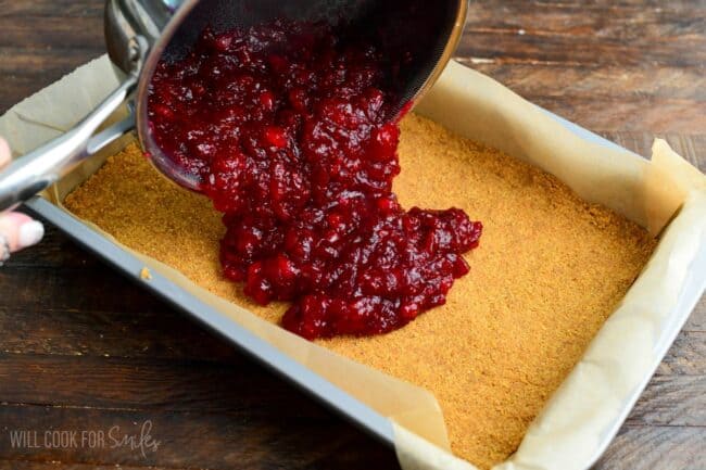 adding cranberry sauce onto the baking pan on top of the crust.