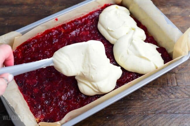 Spreading the cheesecake filling on top of the cranberry sauce.