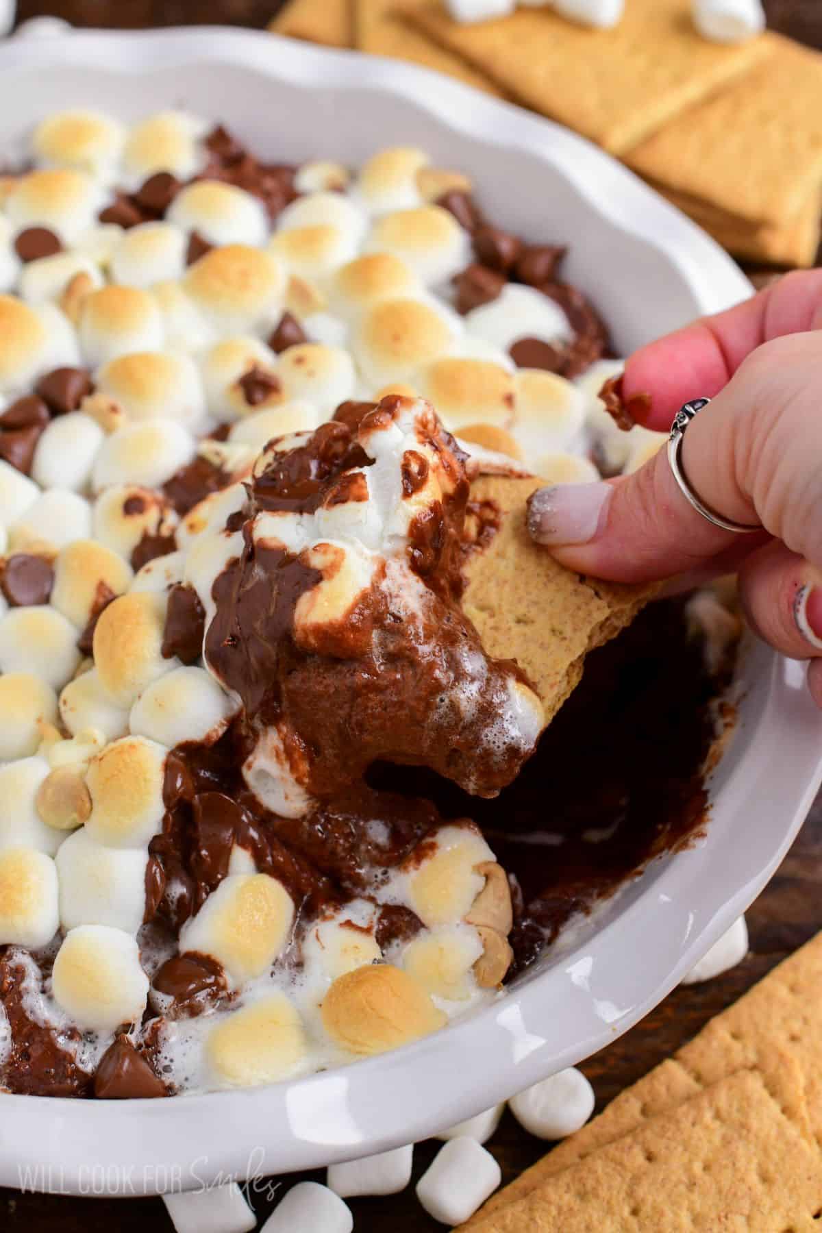 scooping out some warm and creamy chocolate cheesecake dip with gooey marshmallows.