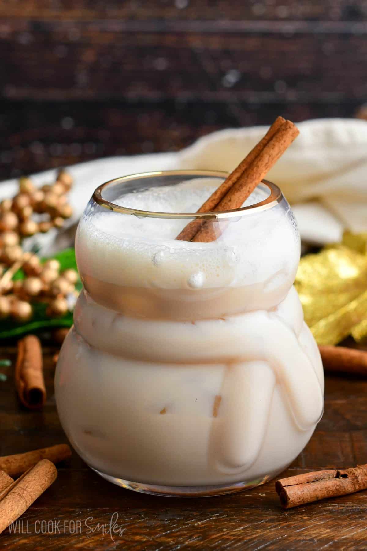 smooth and creamy RumChata cocktail with a cinnamon sick in the glass on a wood surface.