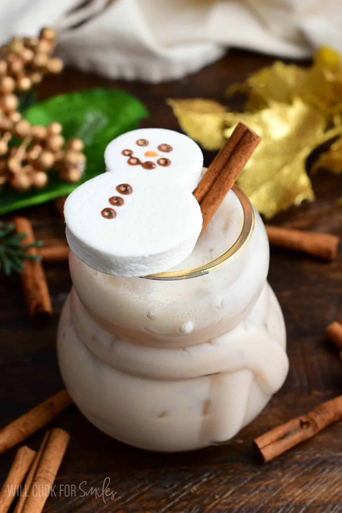 RumChata Cocktail in a glass with a cinnamon stick and a marshmallow snowman on top.