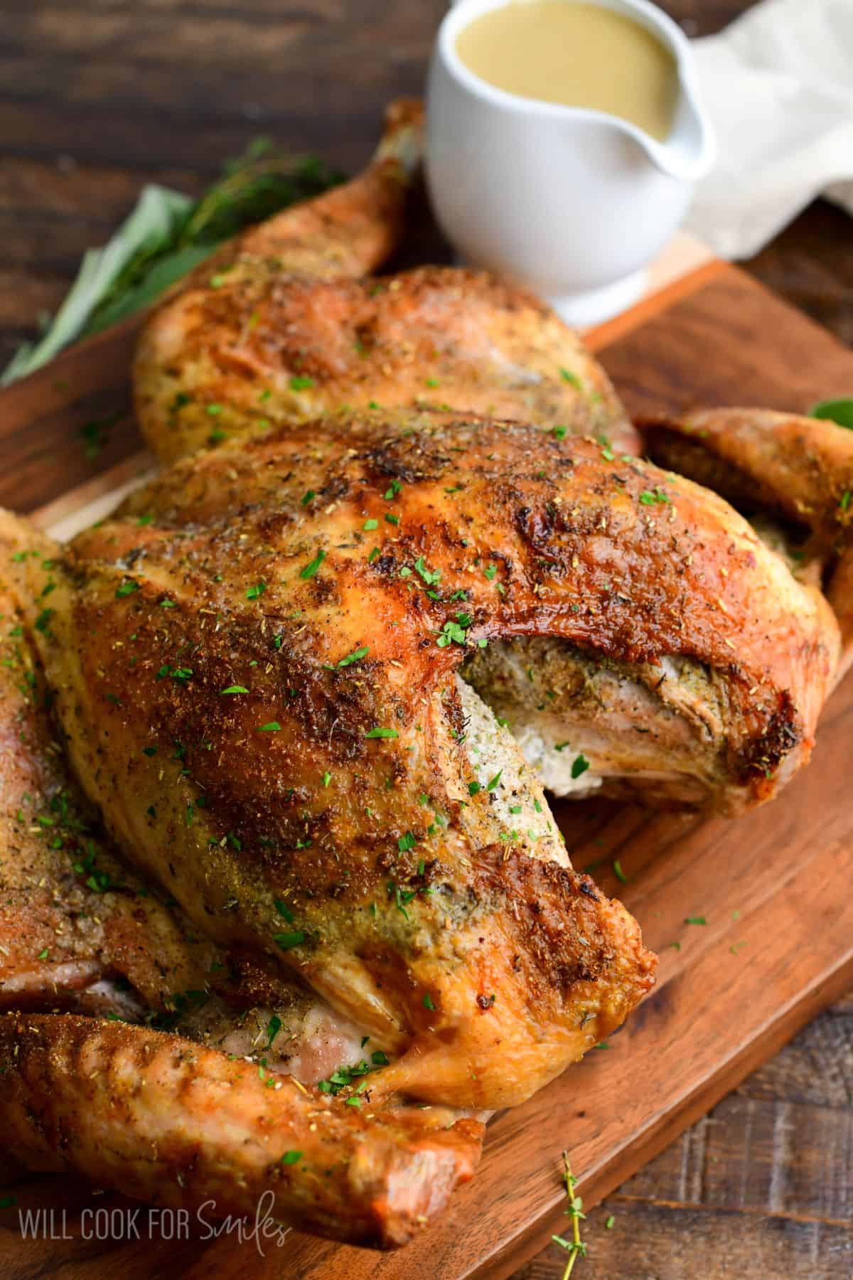 gorgeous golden brown roasted spatchcock turkey with seasoning all around, on a wood cutting board.