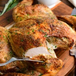 Cutting into the juicy breast of golden roasted spatchcock turkey on a wood cutting board.