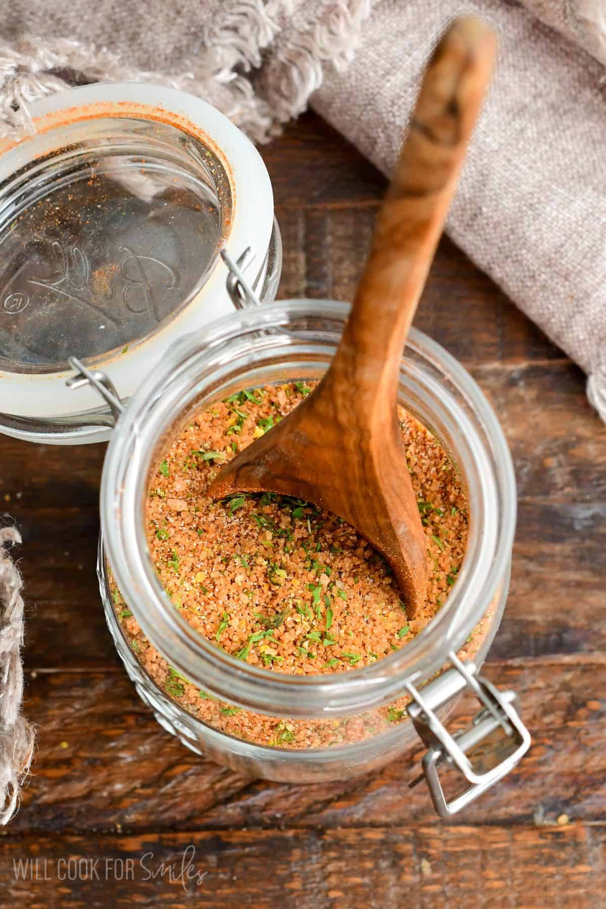 glass jar filled with pork rub seasoning and a wooden spoon in it.