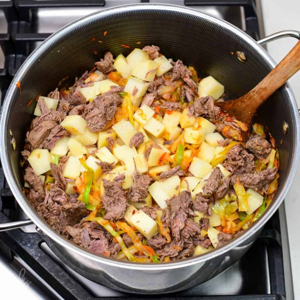 cubed potatoes and cooked tender beef added to the pot with cabbage and vegetables.