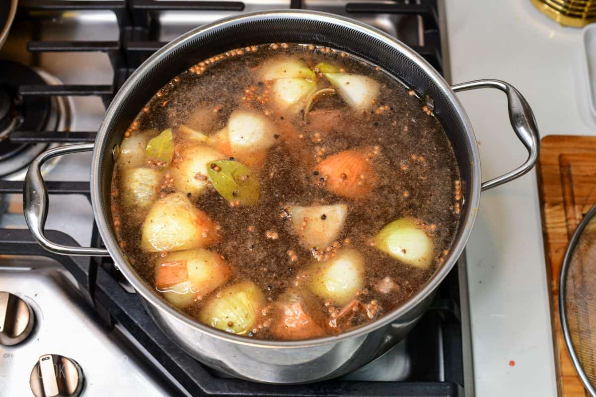 vegetables, beef, been bones, and seasoning all combined with water in a soup pot.