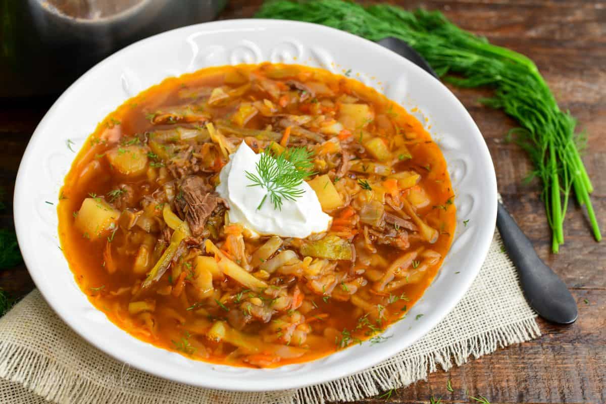 Russian beef and cabbage soup (shchi) in a bowl with a dollop of sour cream and dill.