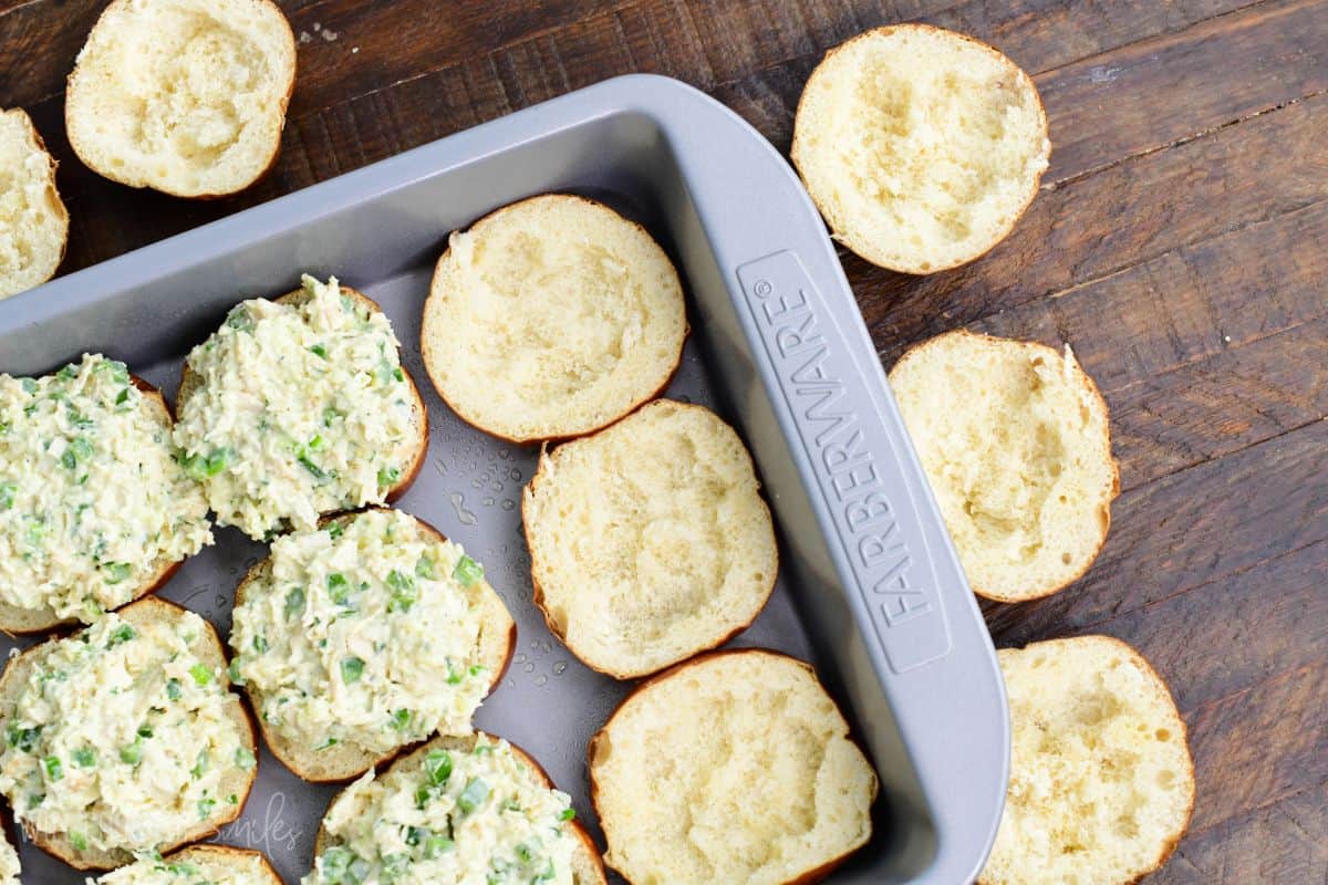 several bottom slider buns, some are filled and some are not with some inside taken out.