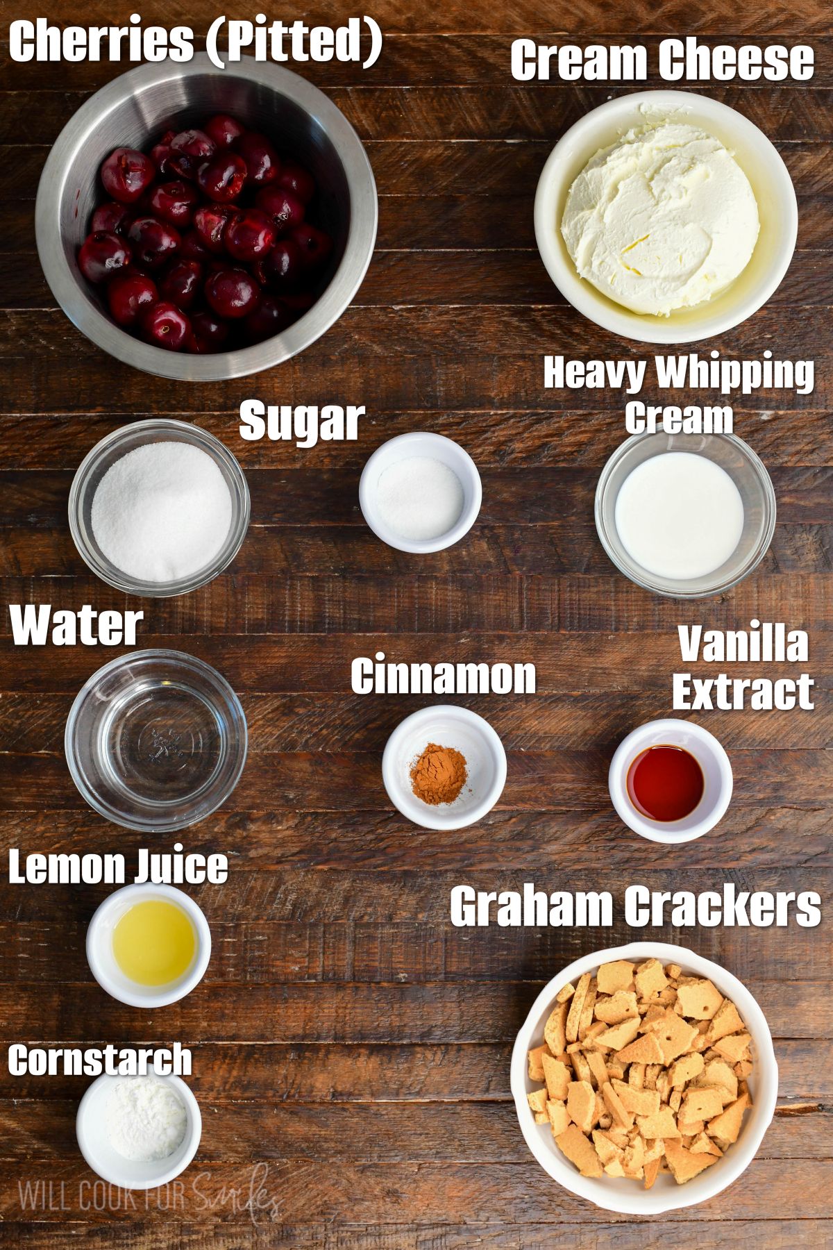 Labeled ingredients for no bake cherry cheesecake parfaits on a wood surface.