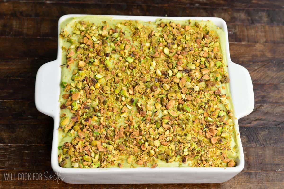 Pistachio tiramisu in a white baking dish topped generously with chopped toasted pistachios, ready to chill or serve.