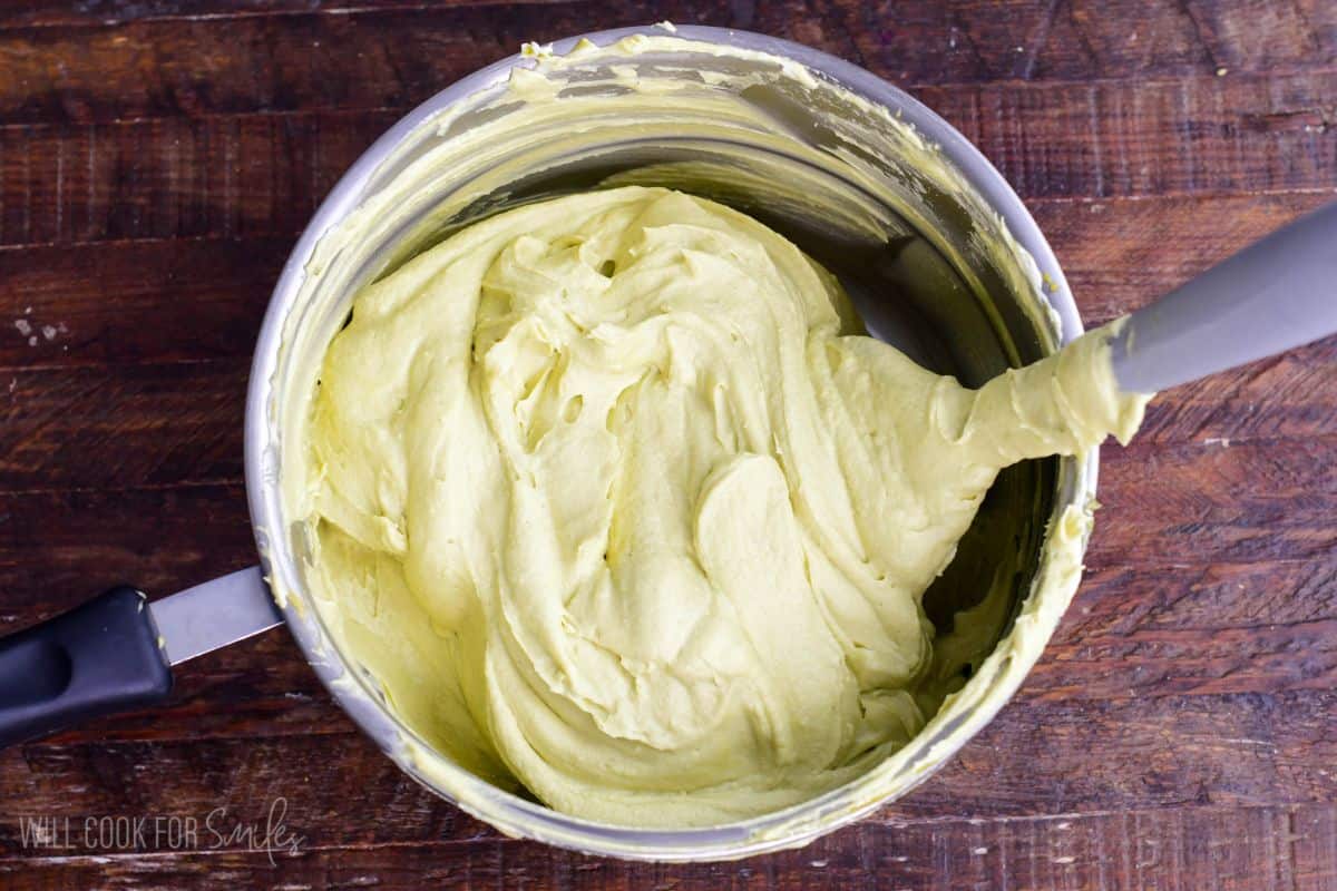 Smooth pistachio mascarpone cream mixture in a saucepan being stirred with a spatula for pistachio tiramisu filling.
